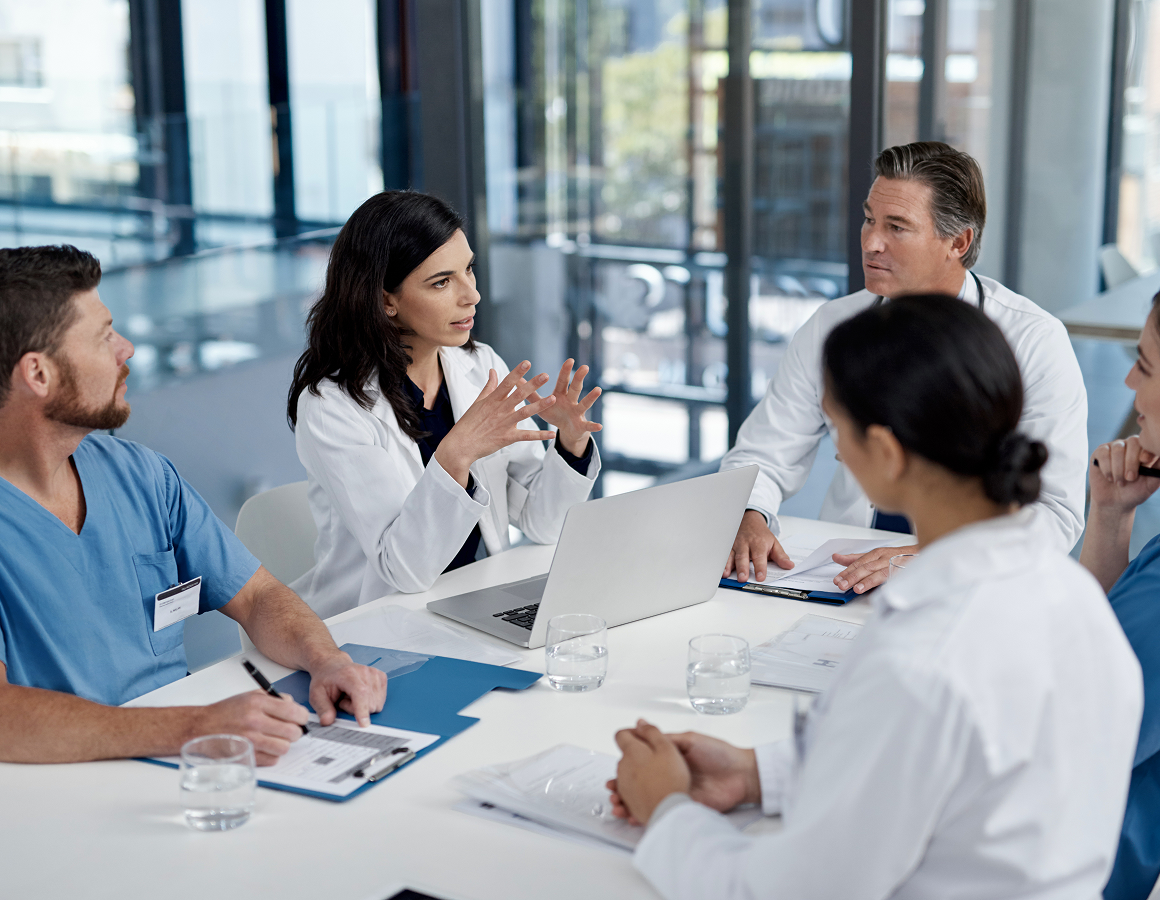 Group of doctors sitting around a table in a meeting room, discussing a patient's diagnosis